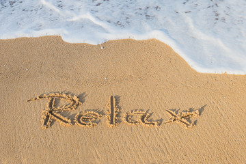 Word Relax handwritten on sandy beach