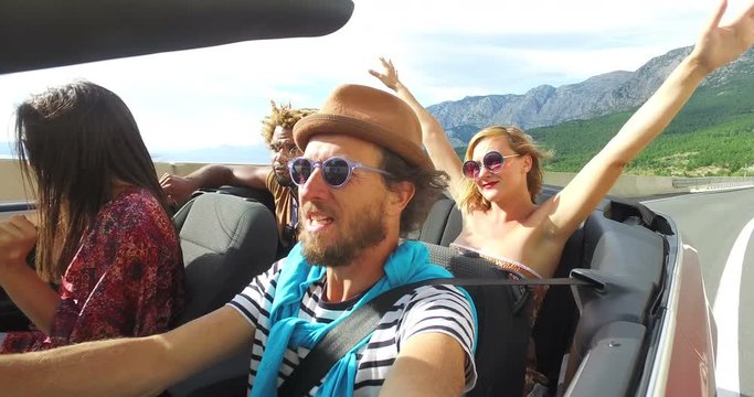 Bearded hipster man with a hat singing with his friends in convertible