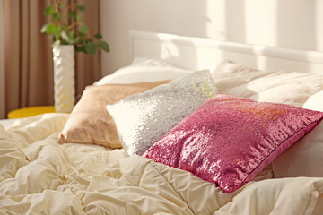 Fototapeta na wymiar Three shiny pillows on bed in modern bedroom