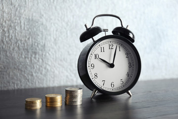 Alarm clock and money on wooden table