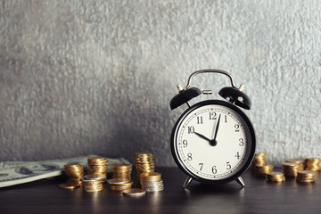 Alarm clock and money on wooden table