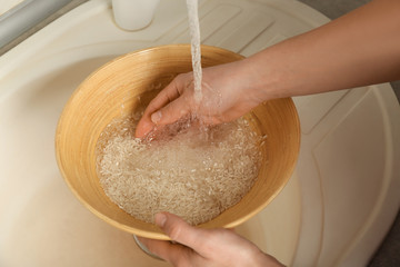 Woman rinsing rice in bowl under running water