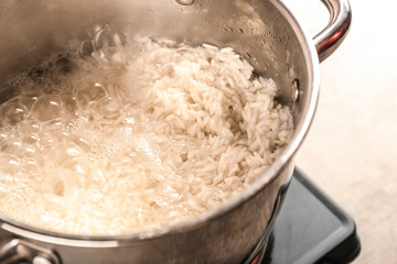 Cooking rice in metal pan on hotplate in kitchen