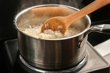 Cooking rice in metal pan on hotplate in kitchen