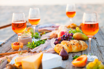 Picnic on the beach at sunset in boho style, food and drink concept