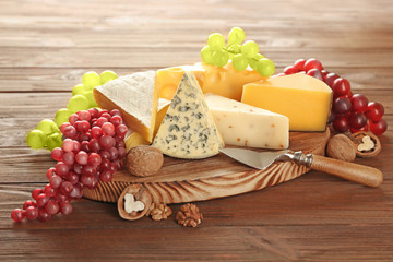 Board with variety of cheese on wooden background
