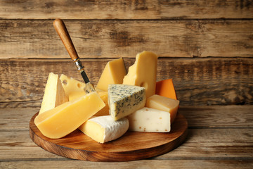 Board with variety of cheese on wooden background