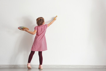 Obraz premium Cute little girl painting on wall in empty room