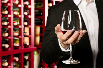 Man with glass of red wine in modern cellar