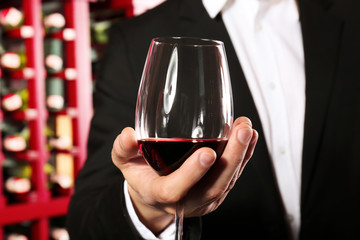 Man with glass of red wine in modern cellar