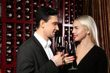 Happy couple drinking in modern wine cellar