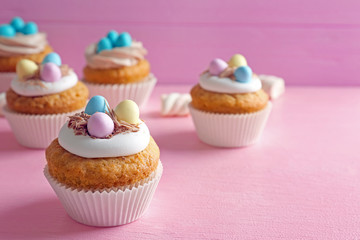 Tasty Easter cupcakes on blurred pink background