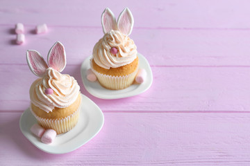 Tasty Easter cupcakes on pink wooden table