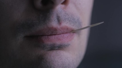 Closeup on the mouth of a tough cool guy smiling while chewing a toothpick. - Powered by Adobe
