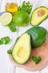 Fresh, green avocado, lime, parsley, sea salt, pepper, bread and eggs for sandwich on a white wooden background