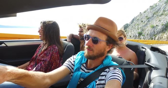 Bearded hipster man with hat driving on mountain motorway with friends