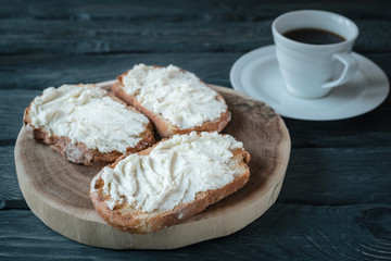 Breakfast with homemade sandwiche with cream-cheese on a black wooden table. Wooden stand with sandwiches.