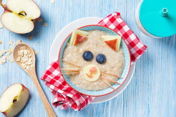 Funny oat porridge with cat, kitten face made of fruit and berries, food for kids idea, top view