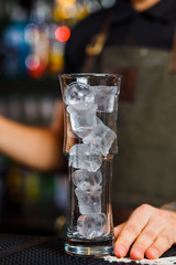 Highball glass with ice standing on bar counter