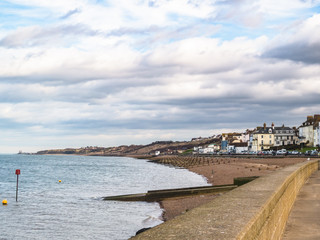The coastline looking towards Reculver Towers of Herne Bay, Kent, UK. The pebble beach has water...