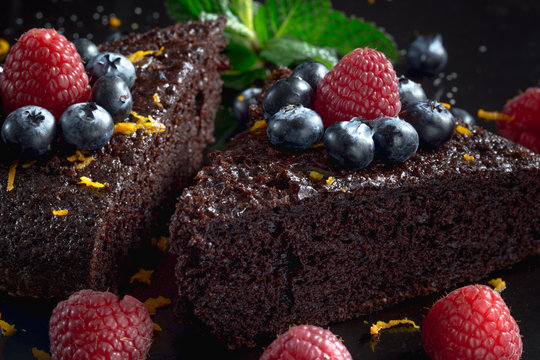 Slices of homemade chocolate cake decorated with raspberries and blueberries.