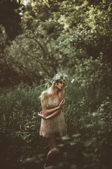 Fashionable toning, creative colors.  Beautiful girl in a dress stay near swamp. Beautiful girl in the a wreath made of flowers. The spirit of the river walking through the swamp