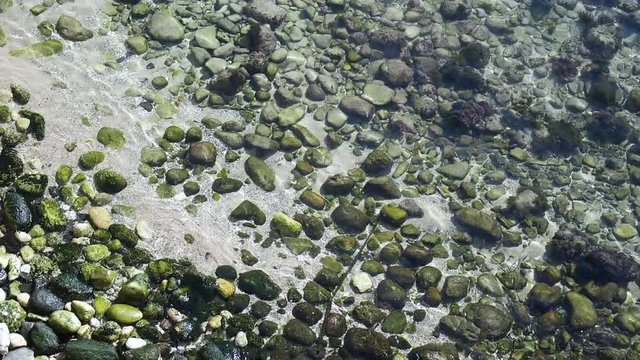 Water waves over pebbles under the sea - green and grey