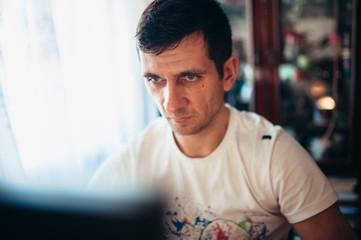 A man sits at home and looks at the monitor with enthusiasm