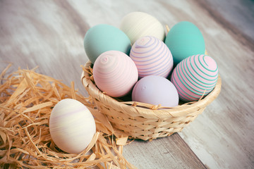 Naklejka na ściany i meble Easter eggs in a basket on wooden boards