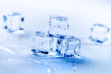 Iced cubes melting on a white table with reflection. Water. Melting of ice.