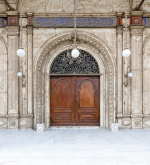 Wooden ornate door over white marble decorated wall. One of the entrances of the Mosque of Muhammad Ali Pasha (Alabaster Mosque), Citadel of Cairo, Egypt