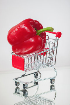 Mini cart, trolley shopping witch organic fresh vegetables, one ripe pepeer on light background. . Concept of healthy food shopping, dieting, vegetarian kitchen