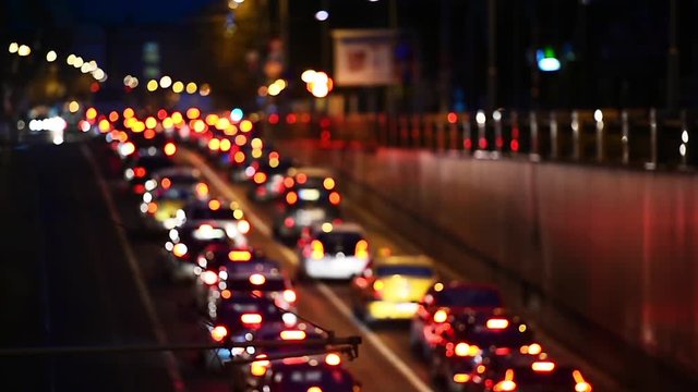 Car lights are seen in a night scene with urban traffic congestion