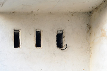 Old ragged plaster white wall with three rectangle ventilation holes