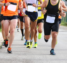 muscular legs of runners during sports race through the streets