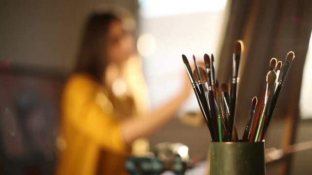 Paintbrushes with painter silhouette painting in background