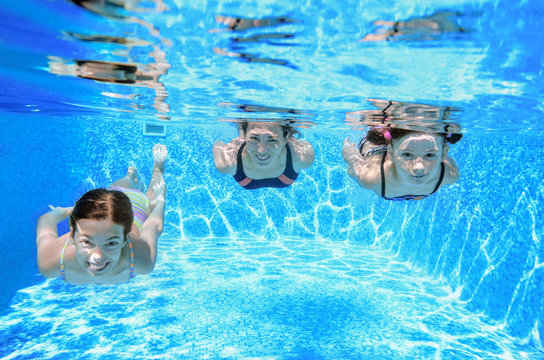 Family swimming in pool under water, happy active mother and children have fun, fitness and sport with kids on summer vacation
