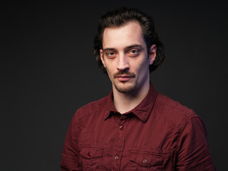 Portrait of a serious man in a burrord shirt, dark gray background