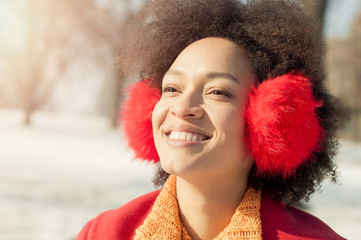 Happy young woman with warm on ears enjoying winter sunshine