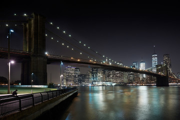 Brooklyn Bridge and New York city skyline illuminated at night with docks