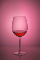 Red wine in the glass. Subject Studio photography. Back-light,. Pink background.