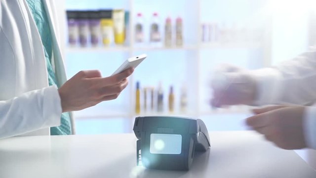 Woman paying through smartphone using NFC technology. Close up. Slow motion.