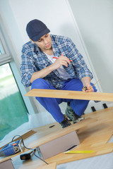 young handyman fitting wooden floor at construction site