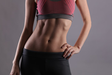 Sport, fit woman. Female with perfect abdomen muscles on grey background. Dieting, fitness, active lifestyle concept, copy space