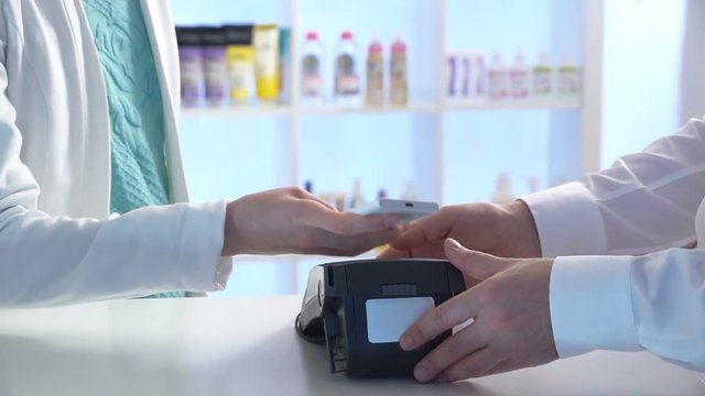 Woman paying through smartphone using NFC technology. Close up. Slow motion.