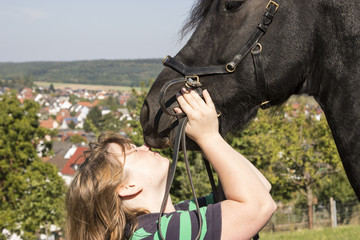 Junge Frau mit neckt sich mit Friesenpferd © Birgit Reitz-Hofmann