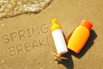 Lotion bottles with starfish on beach sand