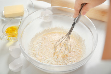 Woman making dough for a pie in a glass bowl