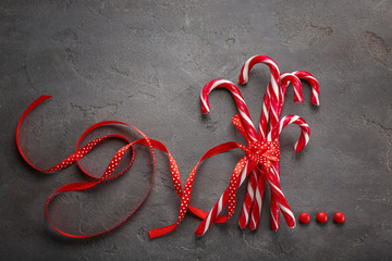 Christmas candy canes tied with ribbon on grey background