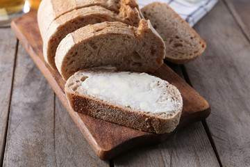 Wooden cutting board with sliced loaf of beer bread and butter on table